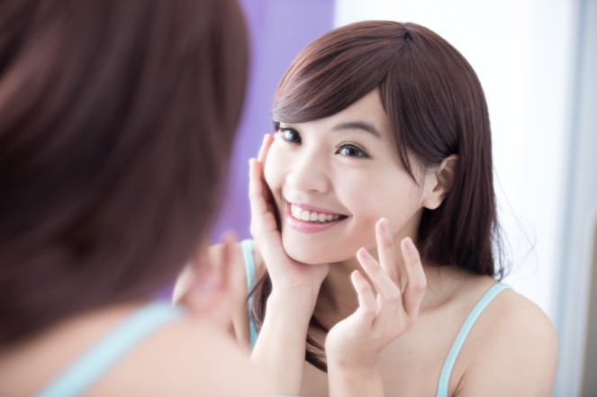 Smile woman applying moisturizer cream